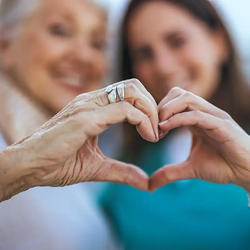 Ältere Frau und jungere Frau bilden mit ihren Händen ein Herz